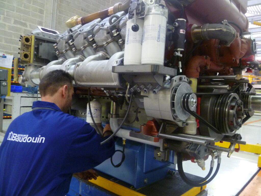 Photo d'un ouvrier de Moteurs Baudoin assemblant un moteur